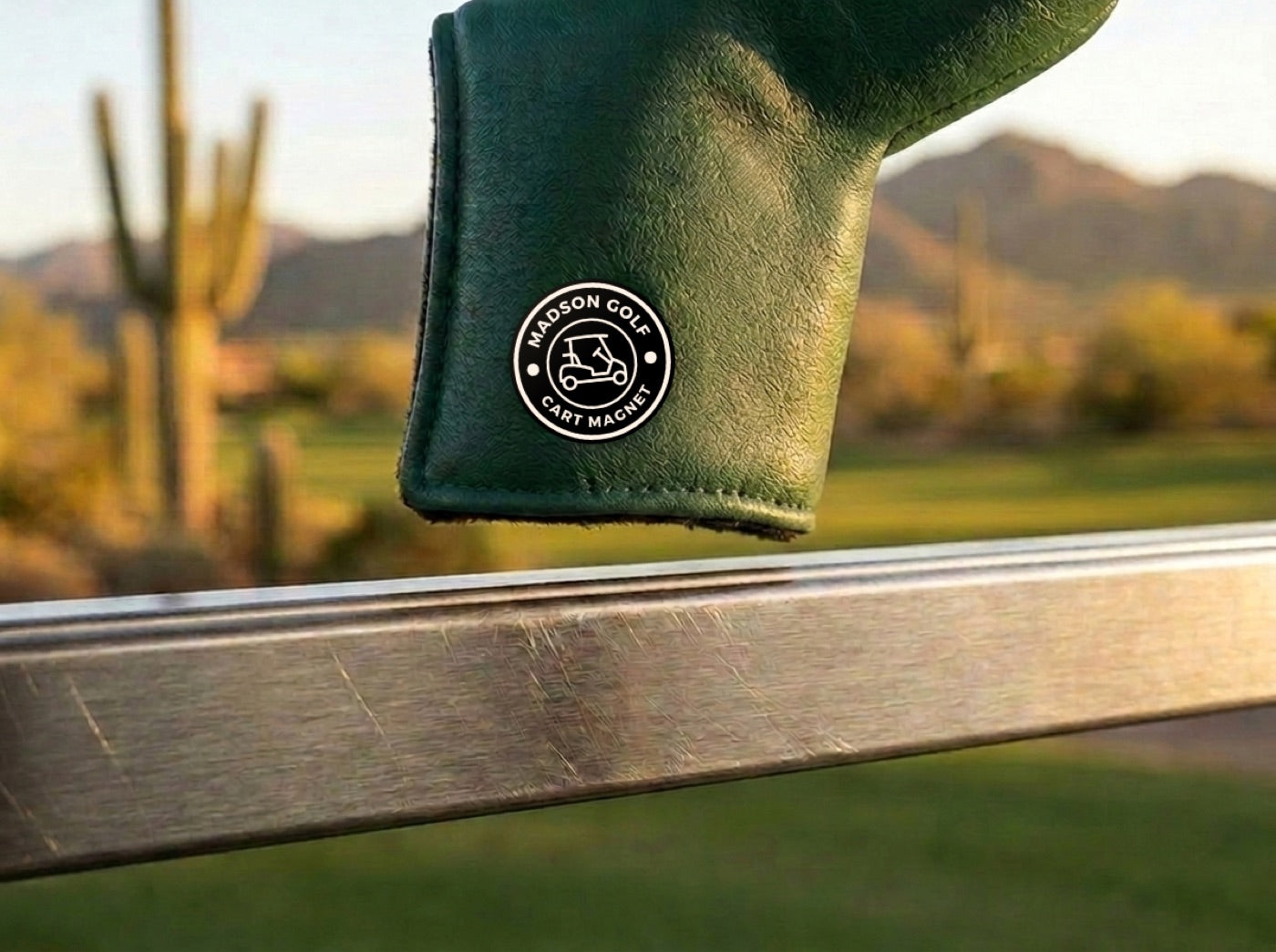 Madson green blade putter cover a few millimeters from snapping onto a golf cart rail